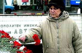 A woman lays flowers outside the entrance to the Avtozavodskaya metro station in Moscow