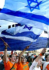 Protesters wave Israeli flags during a march by Gush Katif Jewish settlement bloc residents in the Gaza Strip