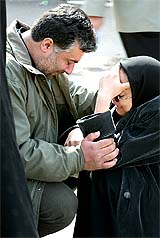 A couple mourns for a relative killed in Iran train blast at a cemetery in Neishabour