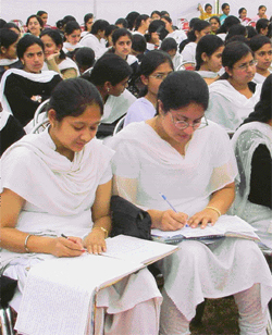 Students of the Khalsa College for Women go through their notes while waiting for the arrival of the chief guest at the annual prize distribution function 