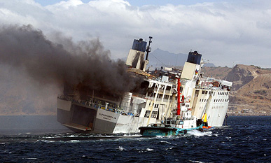 Smoke billows from the still burning passenger ferry after it was towed near the coast off Bataan province, north of Manila