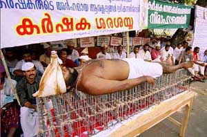 A farmer lying on the bed of sharp metal nails protests in front of the Secretariat