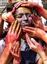 Schoolgirls smear the face of their fellow student with gulal