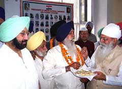 Punjab Congress chief H.S. Hanspal offers sweets to senior Akali leader and former MLA Gurdev Singh Sidhu 