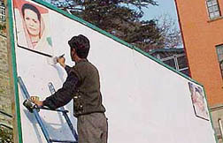 A man erases a message from a hoarding following directions from the Election Commission in Shimla on Wednesday