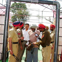 Policemen frisk bidders before allowing them to enter the venue of the liquor shops� auction in Bathinda on Thursday.