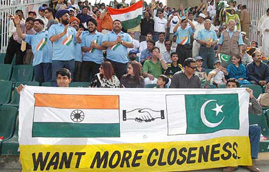 Two spectators hold a banner seeking better relations between the two countries