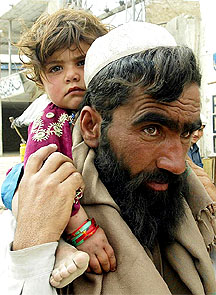 Pakistani tribesman Mohammad Gul carries his daughter Zarmina as he flees from his house near Wana as Pakistani troops intensified their hunt for suspected militants in South Waziristan 
