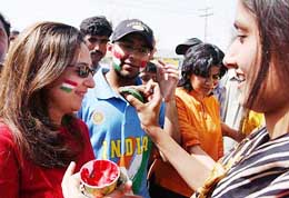 A girl applies colours on the face of Indian supporters outside the Gaddafi Stadium in Lahore