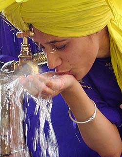 A girl dressed as a boy quenches her thirst as the mercury soars