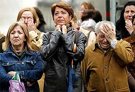 People are overcome by emotion as they watch the state funeral for the 190 victims of the Madrid train bombings on a television screen in downtown Madrid 