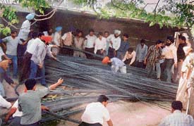 People try to rescue a labourer who got trapped under a truck on the Ferozepore road in Ludhiana 