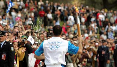 Greek Javelin thrower Kostas Gatsioudis, the first Olympic torchbearer, runs past spectators moments after the Olympic Flame was lit 