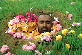 A sadhu, Tapeshwar Bapu, prays as he is buried neck-deep