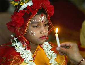 A devotee holds a candle in front of a young girl