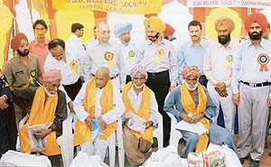 Mr A.P. Bhatnagar, DGP (Jails) along with Dr P.S. Jassi and Mr Gursharanjit Singh, provides aid to elderly persons in Doraha on Monday.