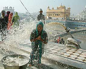A woman enjoys a holy shower as water is being drained out from the rest of the sarovar to pave way for the second phase of kar seva 