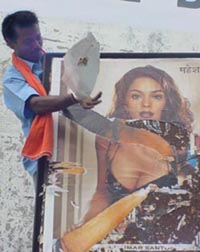 A Shiv Sainik tear away a poster of a movie as part of a campaign to check obscenity