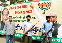 Armed BJP supporters stand in front of a party poster in Patna 
