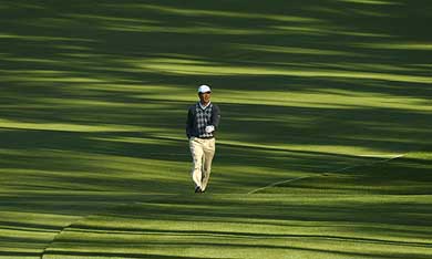 Lian-Wei Zhang of China walks down the second fairway as light filters through pine trees during a practice round for the Masters golf tournament 