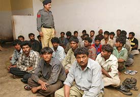 Detained Indian fishermen sit inside a police station in Karachi 