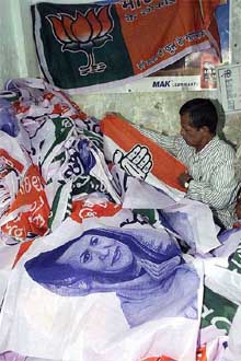 A workman folds banners of the Congress and the BJP to be used for campaign during the Lok Sabha elections