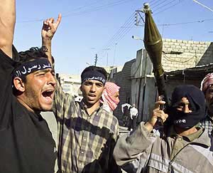 An Iraqi insurgent carries a rocket-propelled grenade launcher in a street after attacking Mosul�s city hall