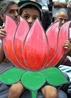A boy holds a cutout of a lotus during a BJP rally at Jammu on Monday