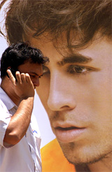 A man talks on his mobile phone as he passes a poster of pop singer Enrique Iglesias