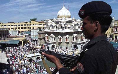A policeman stands guard as thousands of Sikh devotees gather at Panja Sahib