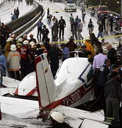 Rescuers surround a small plane that crashed into traffic on a Caracas highway, killing two motorists
