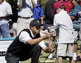 Tiger Woods helps Damon Eames (8) with his swing during a golf clinic at Stryker Golf Course at Fort Bragg, N.C.