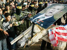 Palestinian masked militants and supporters of Fatah watch as a donkey wearing a picture of US President George W. Bush walks past during a demonstration at Bureij refugee camp in central Gaza Strip on Thursday. 