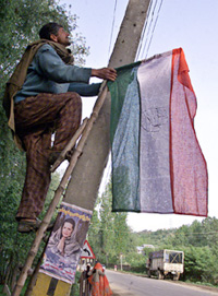 A Kashmiri activist of the Congress climbs a ladder to attach his party�s flag to an electric pole in Baramula