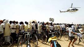 Supporters of the Rashtriya Janata Dal watch as a helicopter carrying party leader Laloo Prasad Yadav arrives at Islampur