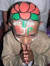 A young boy with his head shaved and coloured with the BJP symbol campaigns in Hubli, Karnataka