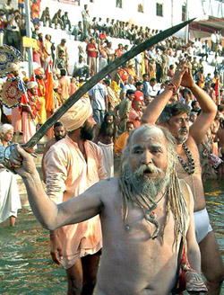 A sadhu raises his sword as others prepare to take a holy dip