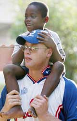 England's Andrew Flintoff carries six-year-old Joseph Rogers on his back during a visit to an orphanage in Port-of-Spain, Trinidad