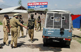 A CRPF officer inspects a damaged vehicle outside a polling booth in downtown Srinagar after a grenade attack