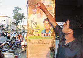 A worker of a party removes posters from public property near Clock Tower after the Deputy Commissioner�s orders
