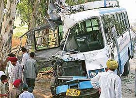 Villagers assemble around the mangled remains of a Haryana Roadways bus which rammed into a tree at Bhankharpur village, near Dera Bassi, in the wee hours
