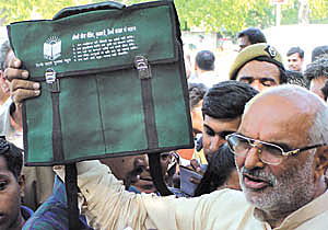 Outer Delhi BJP candidate Sahib Singh Verma showing a school bag bearing the name of Chief Minister Sheila Dikshit 