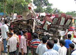 People look at a damaged school bus after a train collided with it at Jalpaiguri, in Silliguri