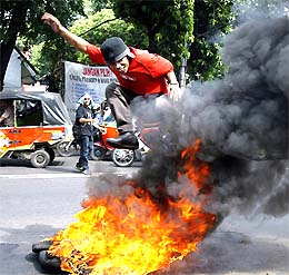 An Indonesian university student jumps over burning tyres during a protest against the candidacy of two former generals in the upcoming presidential elections in Jakarta 