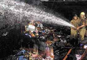 Fire persons trying to douse the flame at a motorcycle dickey factory at Sari Rohilla in the Capital on Wednesday. Three persons died in the fire. 