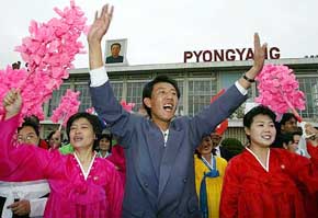 North Koreans wave as South Korean workers arrive at Sunan airport with aid supplies in Pyongyang on Friday.