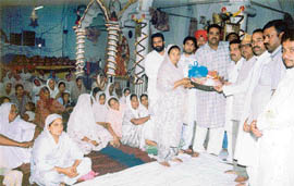 Members of the Punjab Nishkam Seva Dal distribute rations to needy woman at a function organised on Sunday. 