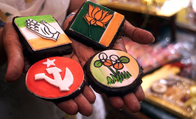 A woman holds cookies, decorated with symbols of different political parties, at a confectionary shop in Kolkata on Monday