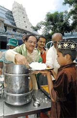 Pakistani ghazal singer Ghulam Ali serves food to a boy at the ISKCON temple in Bangalore