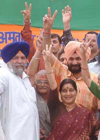 Union Health Minister Sushma Swaraj shows the victory sign with Navjot Singh Sidhu, candidate for Lok Sabha, joining in